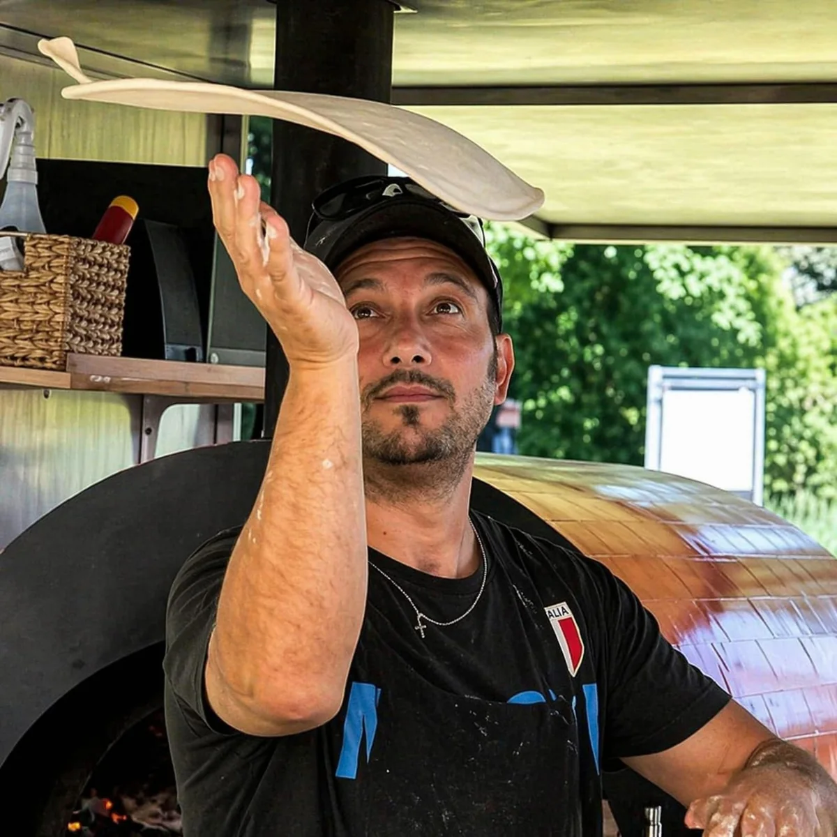 Pietro D’Amico wirft einen Pizzateig vor dem Ofen in die Luft.